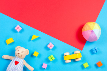 Baby kids toys background. Wooden cars, colorful bricks and soft toys on blue and red color background