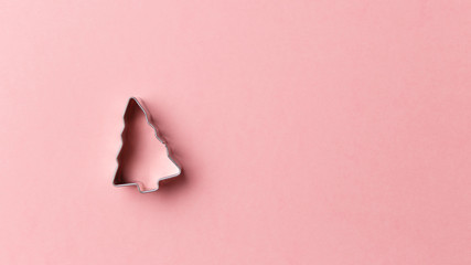 Christmas tree cookie cutter on pink background with copy space. Top view. Flat lay. Trendy...