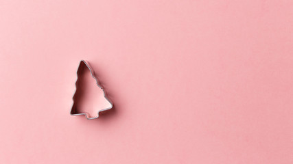 Christmas tree cookie cutter on pink background with copy space. Top view. Flat lay. Trendy colorful photo. Minimal style with colorful paper backdrop. Christmas concept