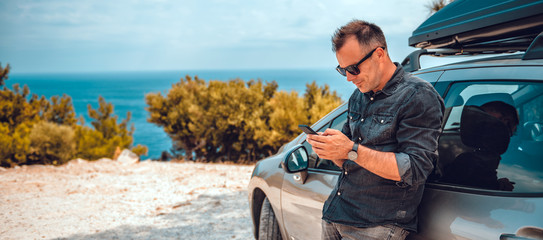 Man lean on car using smart phone