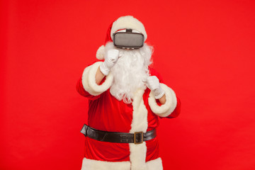 Santa Claus wearing virtual reality goggles, on a red background