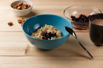 Porridge in a bowl with the berries, walnuts and cocoa on bright wooden table. Healthy breakfast image. Copy space