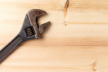 Old, rusty adjustable wrench on wooden background. Top view. Flat lay. Copy space. Close-up