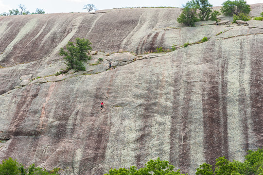 Climbers ascends a granite rock boulder in the Texas Hill Country