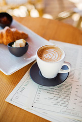 White cup of coffee on wooden table.