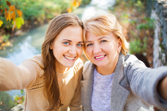 Mother And Adult Daughter Outdoor In Park.