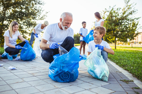 Volunteers with garbage bags cleaning up garbage outdoors - ecology concept.