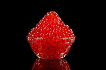 Red Caviar in glass bowl over black background. Close-up salmon caviar.