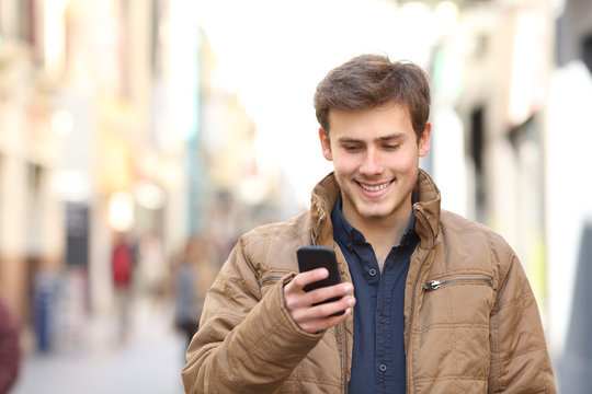 Front view of happy man texing on phone in winter