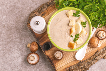 Tasty pureed mushroom soup in clay bowl with ingredients