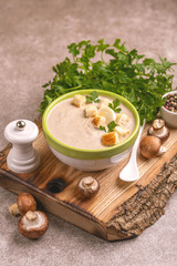 Tasty pureed mushroom soup in clay bowl with ingredients