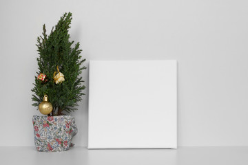 Mock up poster in gray room. White empty canvas and Christmas tree. Christmas and New Year concept.