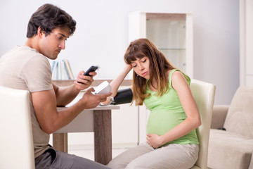Husband checking pregnant wife's blood pressure