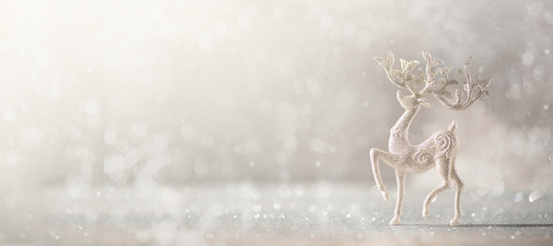 Silver glitter Christmas deer on grey background with lights bokeh, copy space. Greeting card for new year party. Festive holiday concept. Banner