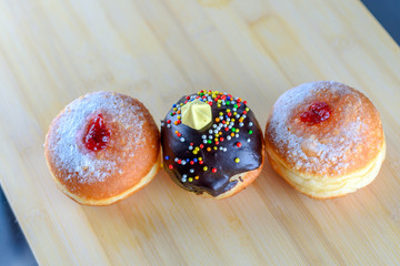 Round jelly doughnut sufganiyot and chocolate sufganiyah for Hanukkah, Jewish holiday on a wooden background.