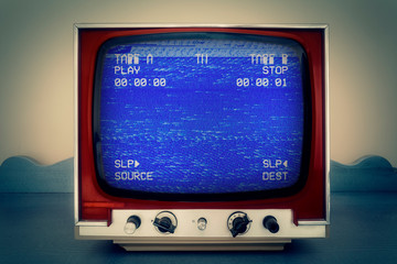 A retro vintage TV showing a VCR double deck tracking an empty noisy VHS tape screen, blue...