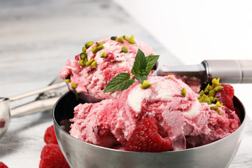 Raspberry ice cream scoop with chopped nuts and white chocolate on a rustic background