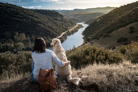 Young girl traveling by nature with backpack and dog