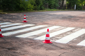 Road cones signal with two reflective stripes on the road with a pedestrian crossing
