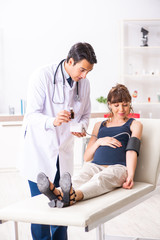 Obraz premium Young doctor checking pregnant woman's blood pressure