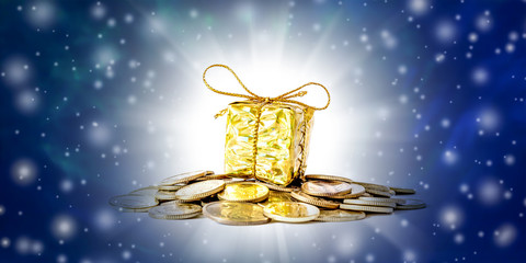 Beautiful Christmas and New Year`s background with coins and gift box in gold packaging, falling snow and free space for text.