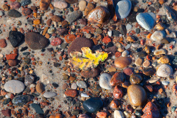 multi-colored pebbles on the bottom under calm crystal clear water
