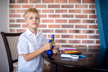 Little boy working with microscope for studying microbes