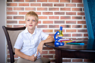 Little boy working with microscope for studying microbes