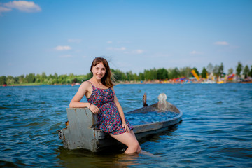 Woman sitting in an old wooden boat on a big lake Svityaz. Concept of the summer