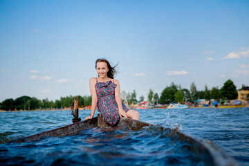 Woman sitting in an old wooden boat on a big lake Svityaz. Concept of the summer