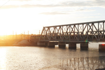 The sunset train passes the railway bridge