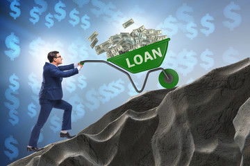 Businessman pushing wheelbarrow uphill in debt loan concept