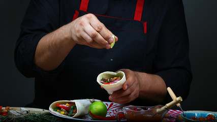 Close up of a chef hands preparing mexican burito. Cook preparing delicious mexican burito at kitchen. The concept of mexican cooking recipe