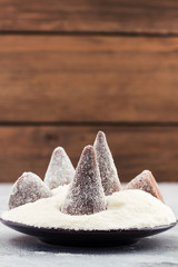 Chocolate truffles in powdered sugar, wooden background, copy space.