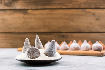 Chocolates in white powdered sugar, wooden background, copy space.