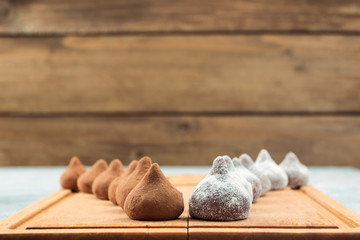 Chocolate truffles, sprinkled with cocoa powder and powdered sugar, located on the kitchen wooden Board in two rows, copy space.