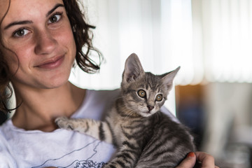 Loveable grey tabby kitten being held with love as teenage girl looks down up.