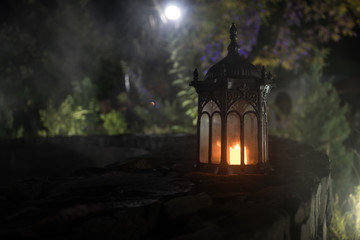 Fototapeta na wymiar Retro style lantern at night. Beautiful colorful illuminated lamp at the balcony in the garden. Selective focus