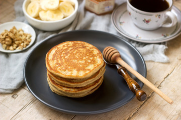 Pancakes with banana, nuts and honey, served with tea. Rustic style.