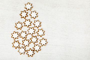 Christmas Tree made of Star Gingerbread Cookies as background on White Wooden Background