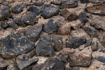 a fragment of a wall assembled from bricks cut from lava and laid on mortar