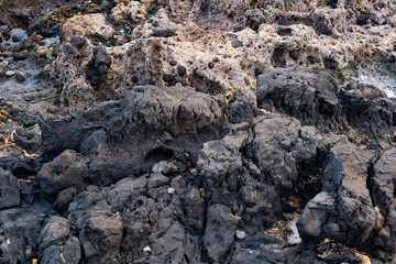 hardened black lava with patches partially polished by ocean waves