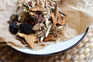 Chinese traditional medicine script. Herbal tea with jujubes, goji berries, gingseng roots and others on parchment paper on neutral background.