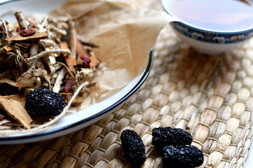 Chinese traditional medicine script. Herbal tea with jujubes, goji berries, gingseng roots and others on parchment paper on neutral background.