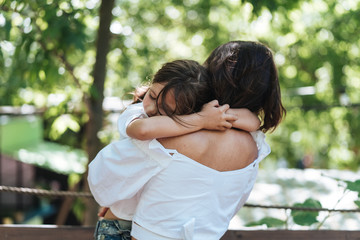Fototapeta premium Young mother hugs her little daughter in the park
