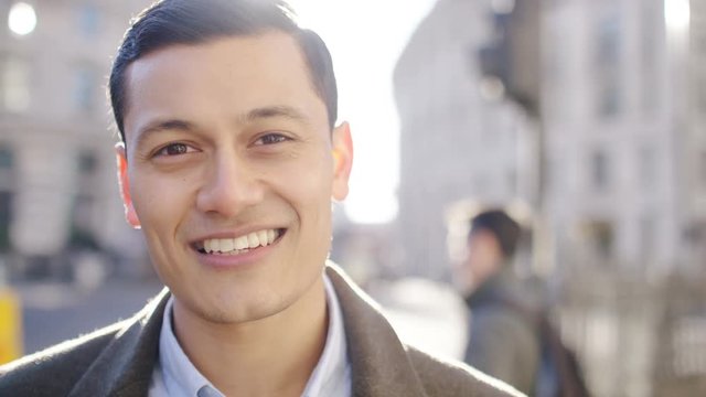 Portrait of handsome mixed race man smiling to camera in the city, in slow motion