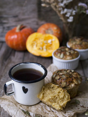 Homemade Autumn Pumpkin Muffins with cheese, paprika and sea salt ready to eat with a metal mug of tea on wooden background. Copy space, close up, selective focus