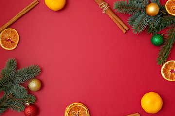 Christmas holidays composition on red background with copy space for your text. Xmas tree branches in the corners, dried oranges, cinnamon sticks. Xmas backdrop for greeting card. Flat lay, top view