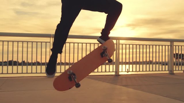 Skateboarder does extreme flip trick at sunset with lens flare 
