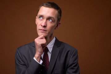 Studio shot of young businessman against brown background